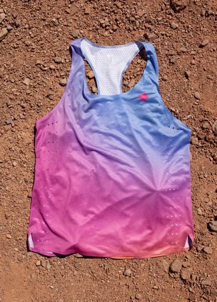 A close-up of the Every Woman's Marathon blue and pink gradient Go Time Singlet against desert floor.