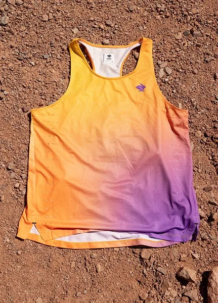 A close-up of the Every Woman's Marathon orange and purple gradient Race Pace Tank Singlet against desert floor.