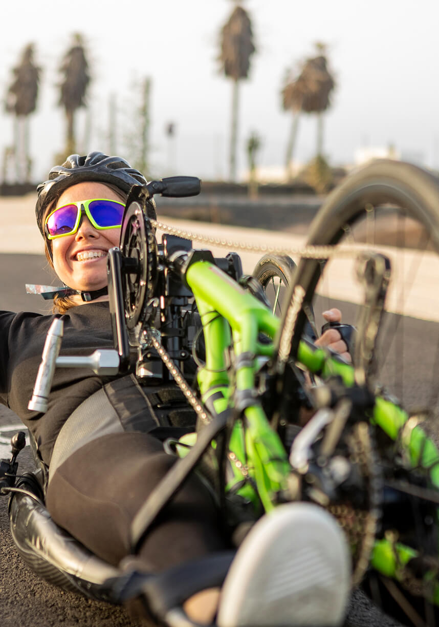 A woman racing on a push rim wheelchair along a road. A woman racing on a push rim wheelchair along a road.