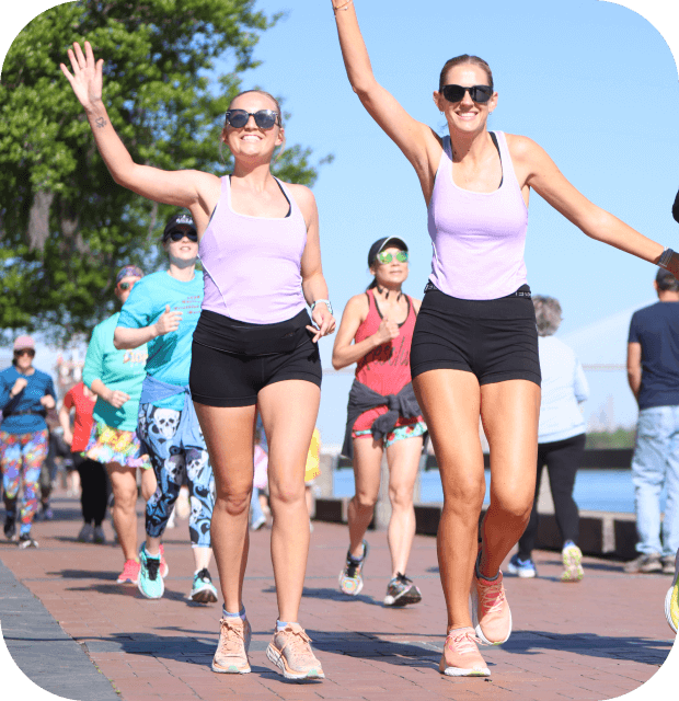 Two women wave as they lead a group of women during a shakeout run.