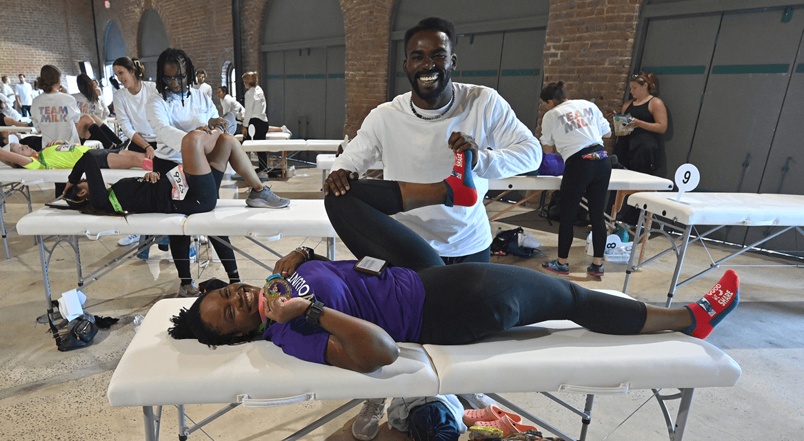 A runner is stretched out by a Team Milk stretch expert after Every Woman's Marathon.