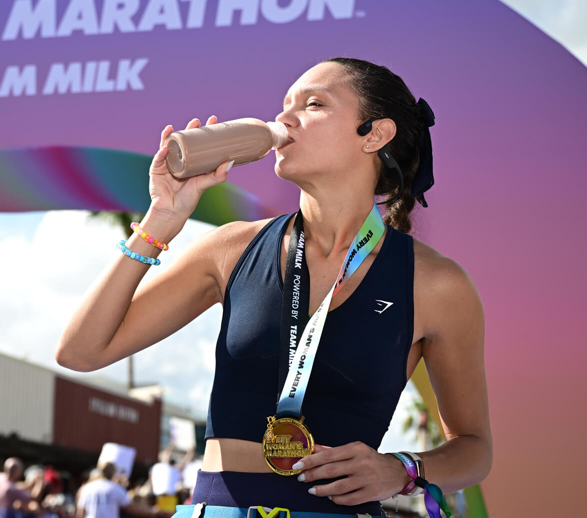 Woman drinks from a refreshing bottle of chocolate milk to aid with muscle recovery after running the Every Woman's Marathon.