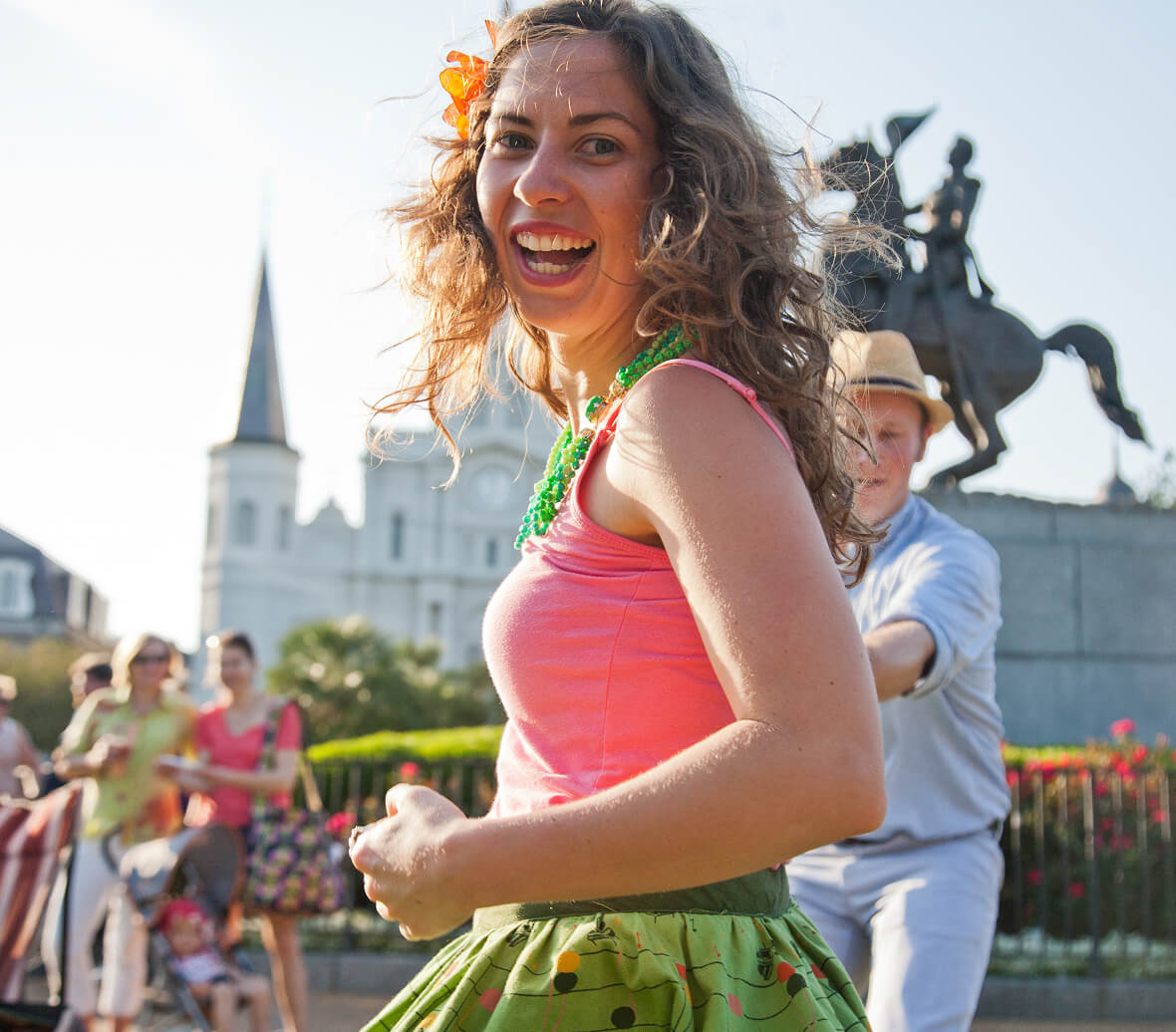 A woman joyfully dancing in the street with a flower in her hair.