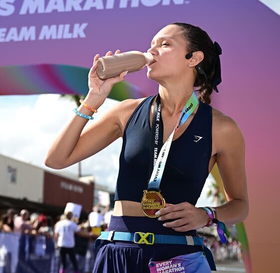 A runner drinks from a bottle of chocolate milk at the finish line of Every Woman's Marathon.