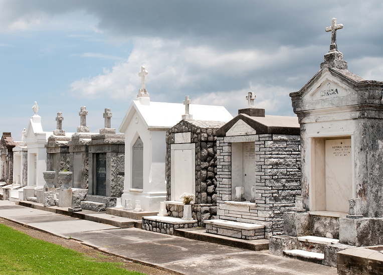 A row of white and stone above-ground tombs adorned with crosses.